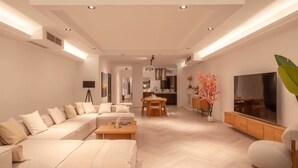 Ein modernes Wohnzimmer mit einem Ecksofa, einem Essbereich und einem Fernseher.