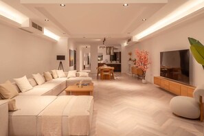 A modern living room with a sectional sofa, a dining area, and a TV.