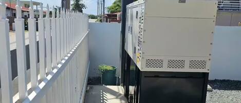 A utility area with a white fence, a large electrical box, and a sign indicating 'Coming Soon'.