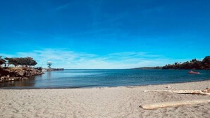 Ein Strand mit klarem, blauem Wasser, einem Steg und einem roten Boot.