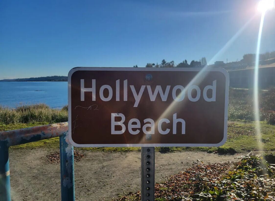 Ein Schild mit der Aufschrift 'Hollywood Beach', im Hintergrund ist der Strand und das Meer deutlich zu sehen.