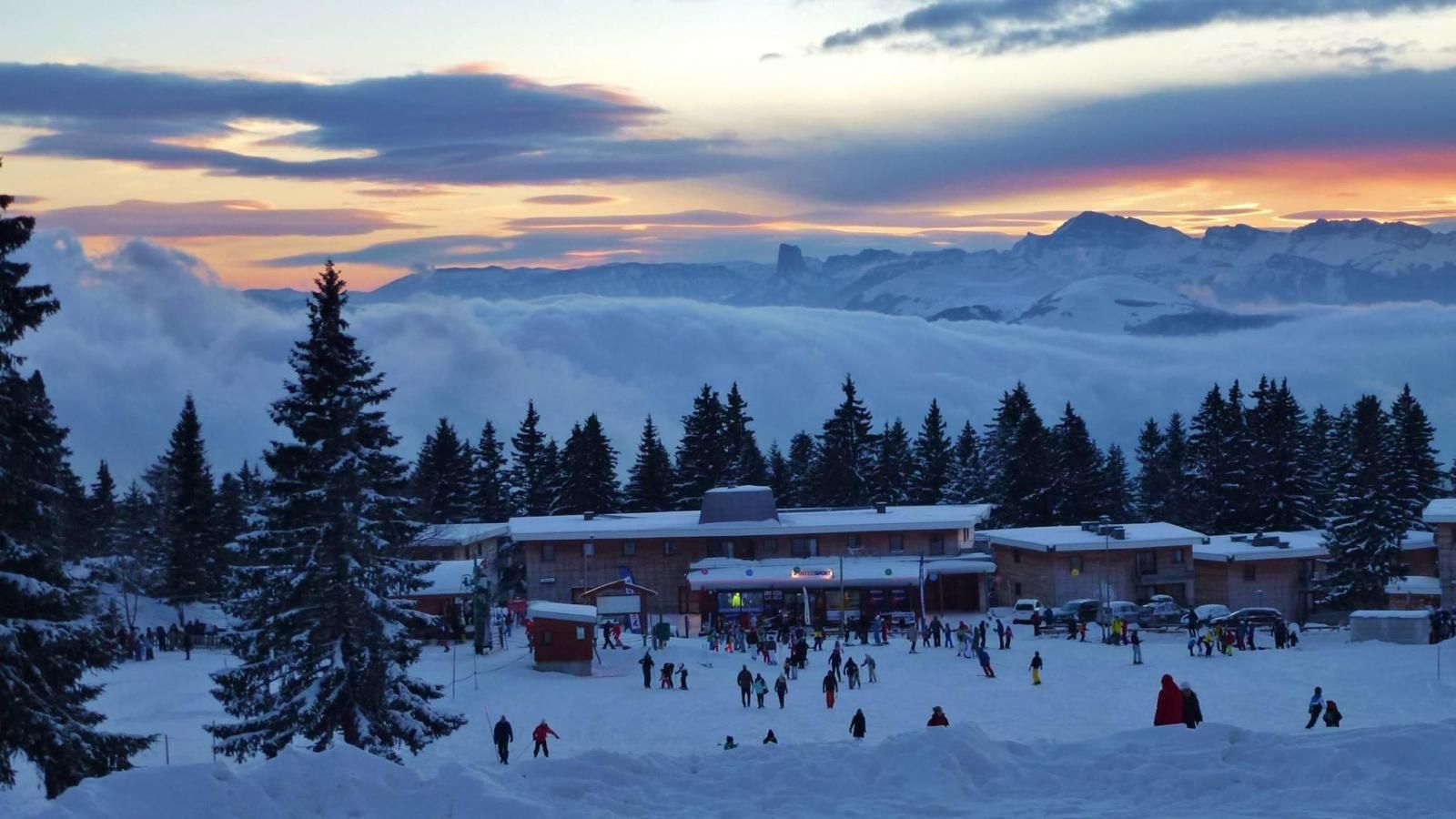 Une station de ski enneigée, avec des bâtiments et une foule de personnes.