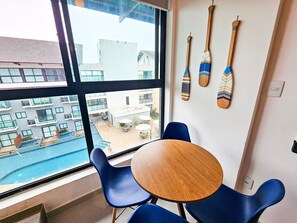 A room with a large window, a wooden table, blue chairs, and wooden paddles on the wall. - Condomínio Bela Vista Porto de Galinhas (Ipojuca)