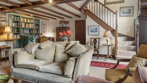 Un salon chaleureux avec un canapé, une bibliothèque, une cheminée et un escalier.