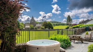 Un bain à remous dans un jardin offrant une vue sur une église et des champs verdoyants.