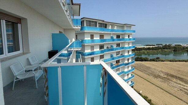 Ein mehrstöckiges Hotel mit Balkonen, einem Poolbereich und Blick auf das Meer.