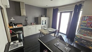 A compact kitchen with a dining area, a coffee machine, a sink, and a window with curtains. - A charming gite (Sainte-Luce-sur-Loire)