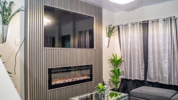 Un salon moderne avec une cheminée intégrée, une table basse en verre et un canapé gris.