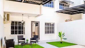 Un vaste espace patio aménagé avec des sièges, une pelouse artificielle et un pot de fleurs.
