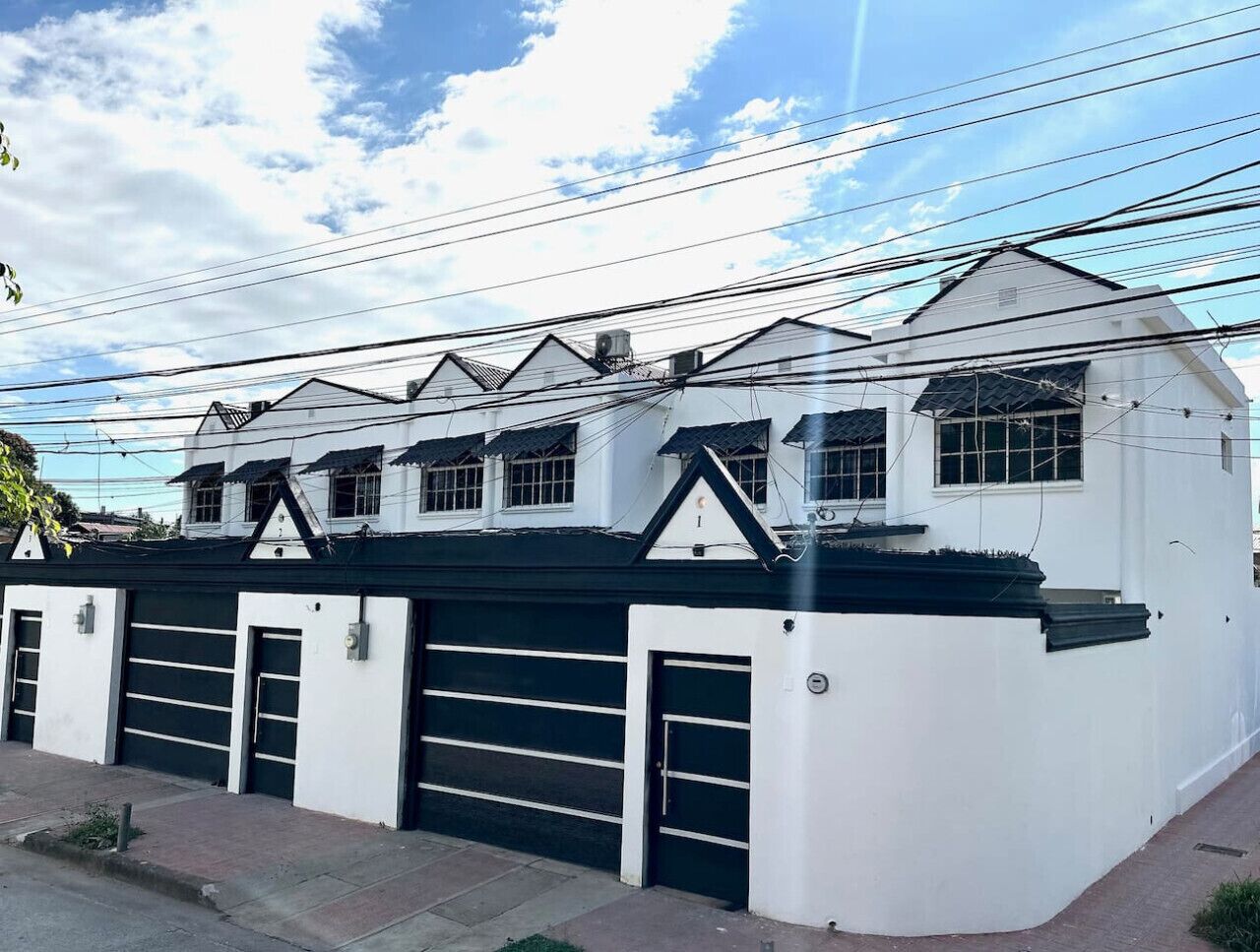 Un edificio blanco con varias puertas de garaje y techo negro.