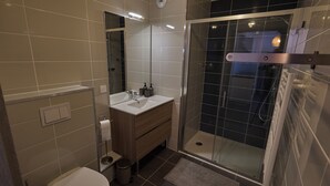 Ein modernes Badezimmer mit Duschkabine aus Glas, einem Waschbecken mit Spiegel und einer Toilette.