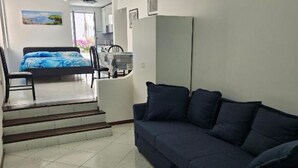A room with a bed, a sofa, and a staircase leading to a balcony.