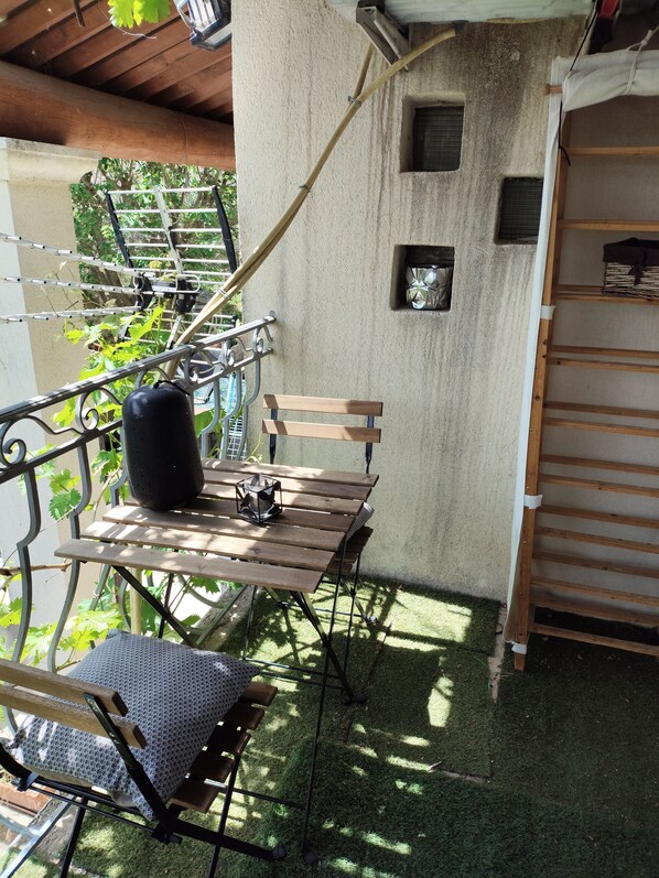 A patio with a wooden table and chairs, a hanging clothes rack, and a small window. - Quiet apartment at the foot of the Luberon (Mérindol)