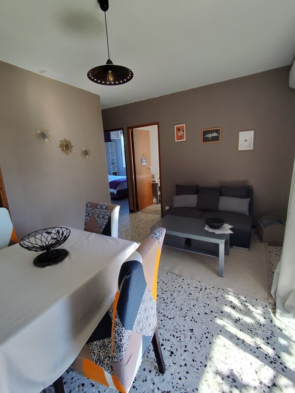 Un salon moderne comprenant un coin repas, un ensemble de canapés, une table basse et un ventilateur de plafond.