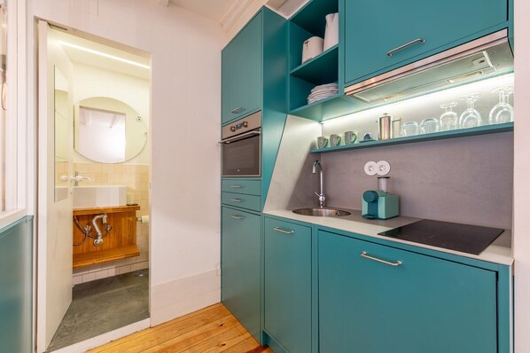 Een moderne keuken met blauwgroene kastjes, een ingebouwde oven en een spoelbak.