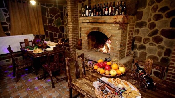 Un comedor rústico con chimenea de piedra, muebles de madera y una variedad de alimentos y bebidas sobre la mesa.