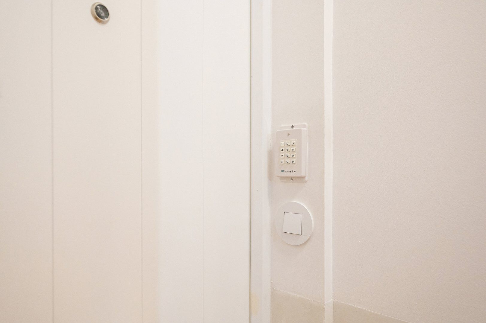 Une porte blanche avec une serrure et un système d’interphone fixé au mur.