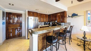 A kitchen with wooden cabinets, a granite countertop, and a bar area with bar stools.