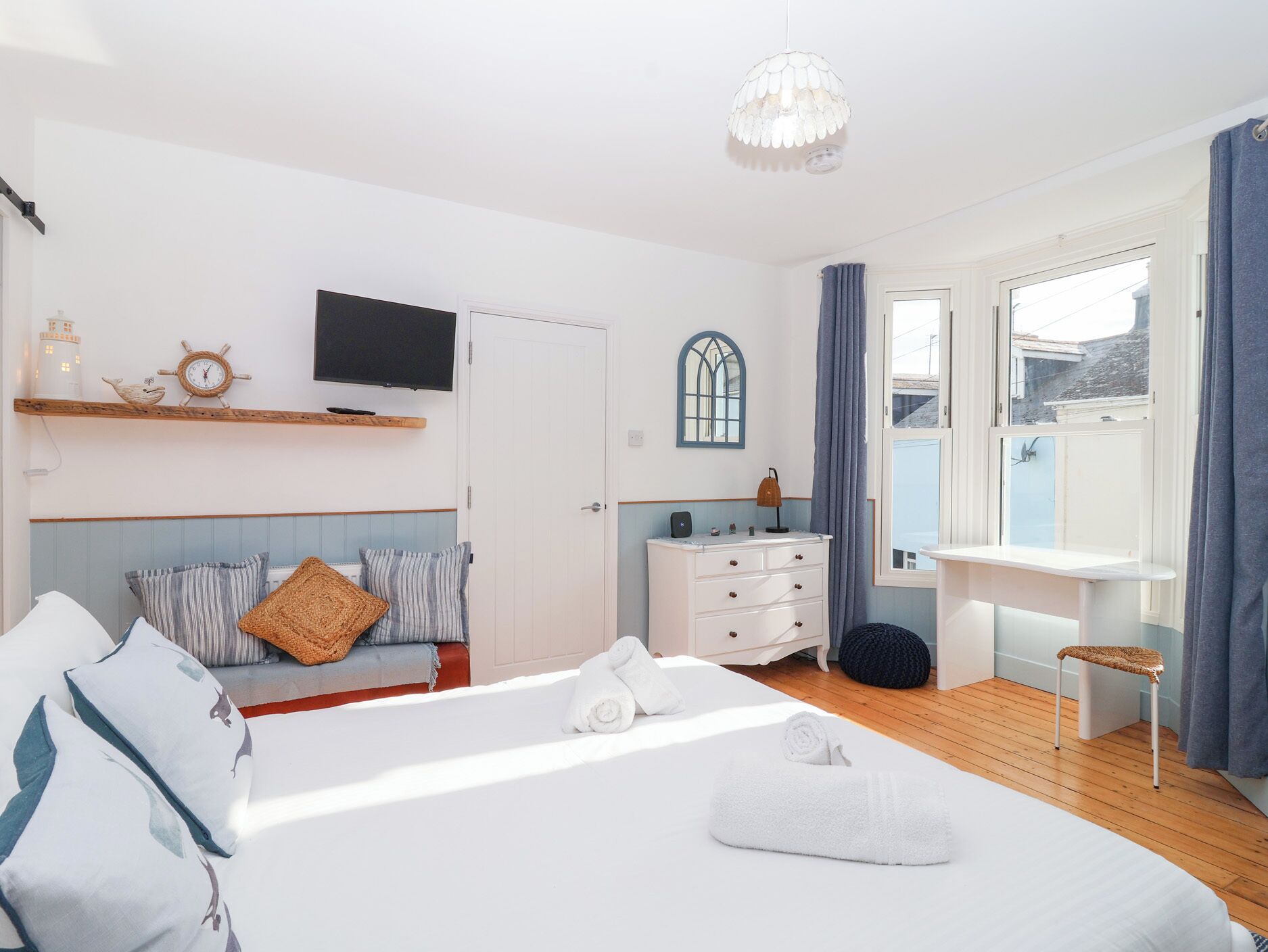 Une chambre à coucher comprenant un lit, une table de chevet, une commode et un téléviseur fixé au mur.