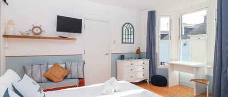 Ein Schlafzimmer mit Bett, Nachttisch, Kommode und einem an der Wand befestigten Fernseher.