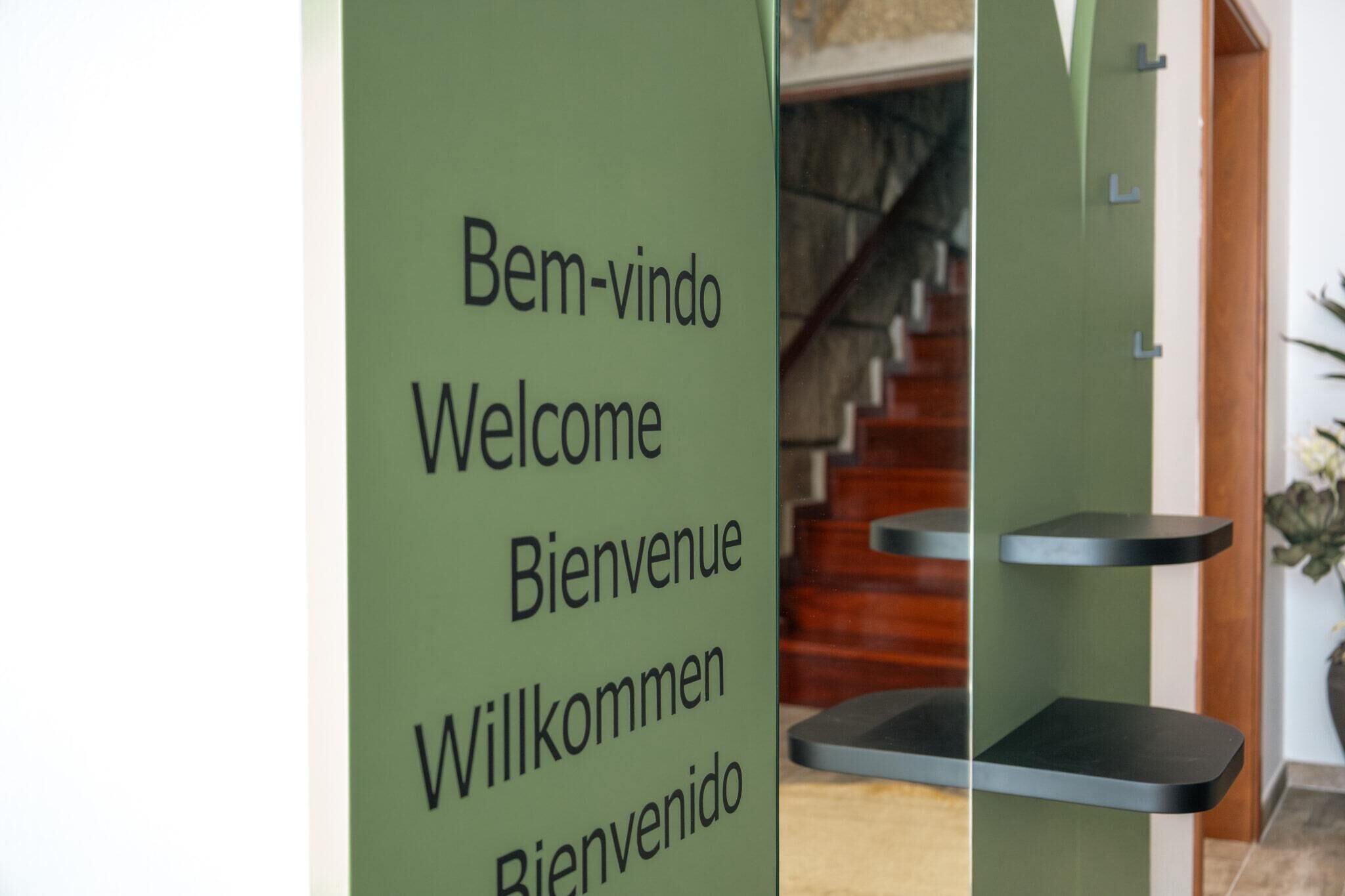 A green welcome sign with multilingual greetings in a hotel lobby.