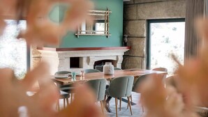 A dining area with a stone fireplace, a wooden table, and grey chairs. - Douro Sky Valley (Miomães)