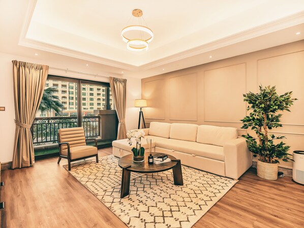 A modern living room with a sofa, armchair, coffee table, and a potted plant.