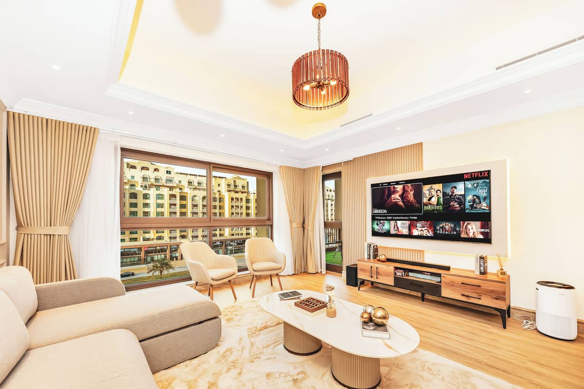 Een moderne woonkamer met een grote televisie, zachte zitplaatsen en uitzicht op de stad door grote ramen.