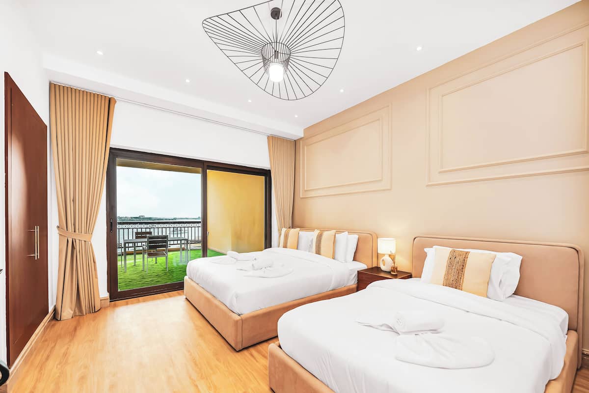 Een hotelkamer met twee bedden, een balkon en uitzicht, en een moderne plafondlamp.
