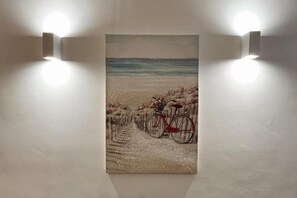 A painting of a bicycle on a beach with a fence in the background.