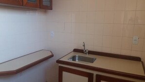 A small kitchen with a sink, wooden countertop, and cabinets.