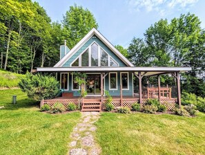 Ein Haus mit überdachter Veranda, einem gepflasterten Weg zum Eingang und einem üppigen grünen Rasen.