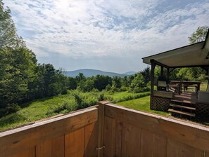 A wooden deck with a view of a green landscape and mountains in the distance. - Cozy Catskills A-frame hideaway (Margaretville)