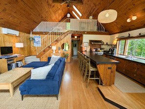 A wooden interior with a living area, kitchen, and a staircase leading to an upper level. - Cozy Catskills A-frame hideaway (Margaretville)
