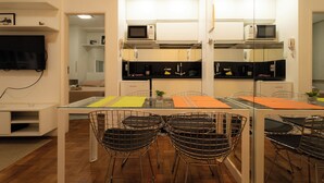 Una cocina moderna con comedor, que incluye una mesa de vidrio, sillas de metal y un microondas.