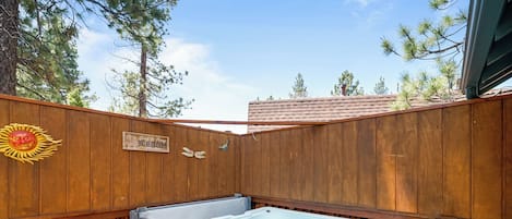 A wooden fence with a hot tub and a sign that reads "Big Bear Cabin."
