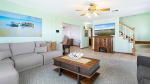 A spacious living room with a grey sofa, a wooden coffee table, and a ceiling fan. - Bayou Manor: 3BR House (Slidell)