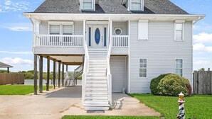 A two-story house with a covered front porch, a front door, and a staircase leading to the second floor. - Bayou Manor: 3BR House (Slidell)