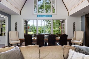 A dining area with a view of a lake, a sign reading 'LAKE HOUSE', and a high ceiling with wooden beams. - Smith Lake Serenity (Jasper)