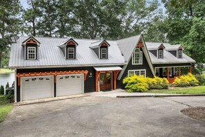 A two-story house with a garage, a covered porch, and a pond in the background. - Smith Lake Serenity (Jasper)