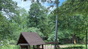 A wooden play structure with a climbing wall and swings.