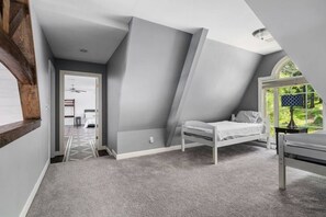 A bedroom with a sloped ceiling, a single bed, a nightstand, and a window with a view of greenery. - Smith Lake Serenity (Jasper)