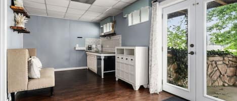 Una cocina moderna con armarios blancos, un comedor con una silla color beige y vistas a través de un ventanal.