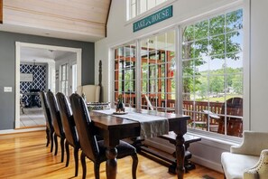 A dining area with a large table and chairs, a view of the outdoors, and a sign reading 'LAKE HOUSE'. - Smith Lake Serenity (Jasper)