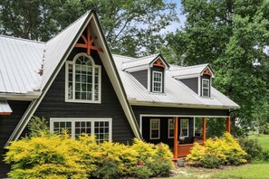 A dark-colored house with a prominent gable roof and a porch with a railing. - Smith Lake Serenity (Jasper)
