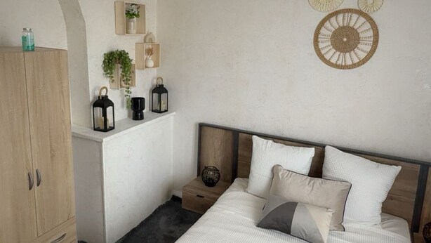 Quarto com cama, mesas de cabeceira, guarda-roupa, luminária na parede e decoração de parede.
