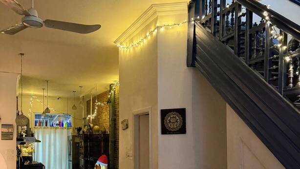 Ein Wohnzimmer mit einer dunklen Treppe, Deckenventilator und Lichterkette.