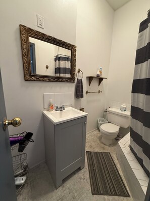 A bathroom with a sink, toilet, and a shower curtain. - The Macaw Guesthouse (New York)