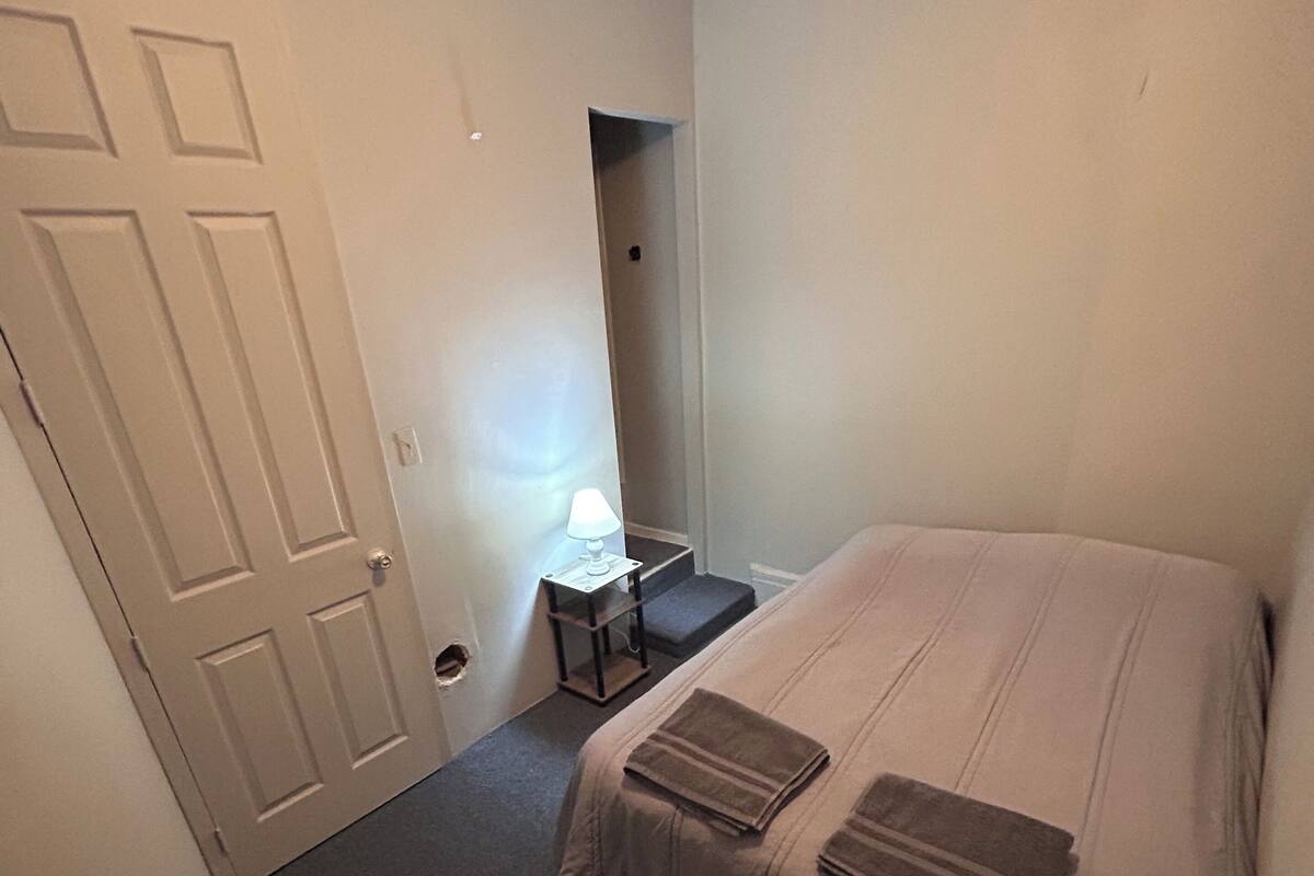 A bedroom with a bed, a desk, and a chair.