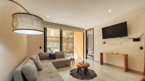 A modern living room with a sofa, a coffee table, a TV, and a console table. - Aldea Savia hideaway in Tulum (Tulum)